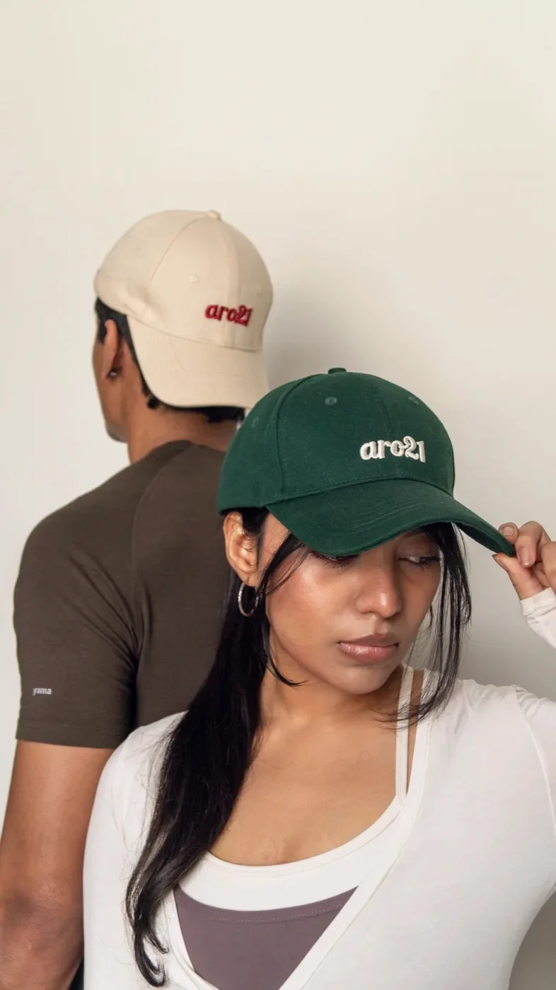 Two people wearing the aro21 cap, one in Dawn cream and one in Grove green